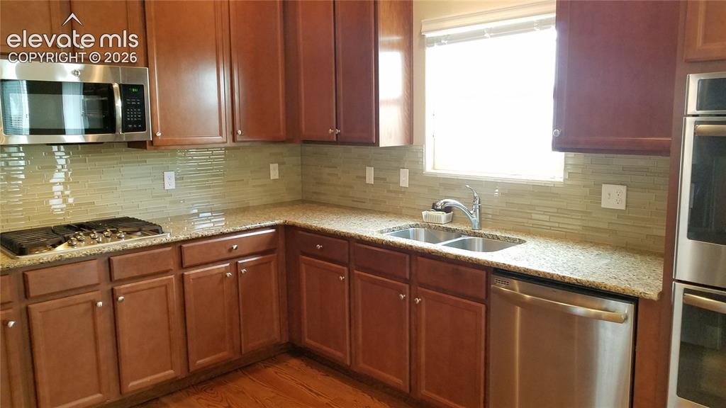 Image 7 of 32: Kitchen featuring wood-finish cabinetry, stainless steel appliances, speckl