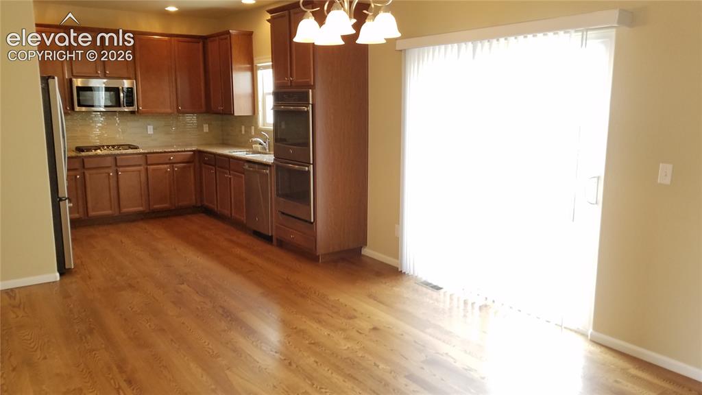 Image 8 of 32: Open-concept kitchen and dining area featuring wood-finish flooring, warm w