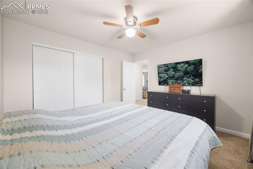 Image 13 of 15: Bedroom with light colored carpet, a closet, and a ceiling fan