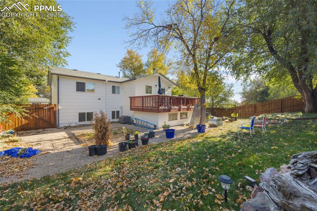 Image 15 of 15: Rear view of property with a fenced backyard, a wooden deck, and a patio ar