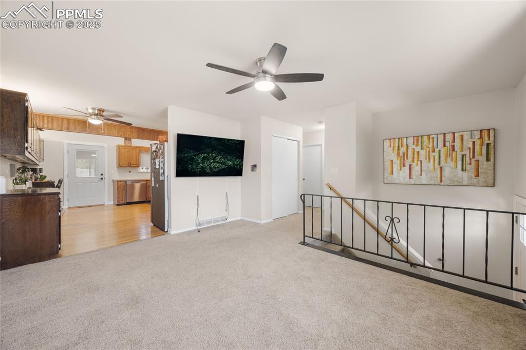 Image 3 of 15: Unfurnished living room featuring light colored carpet and a ceiling fan