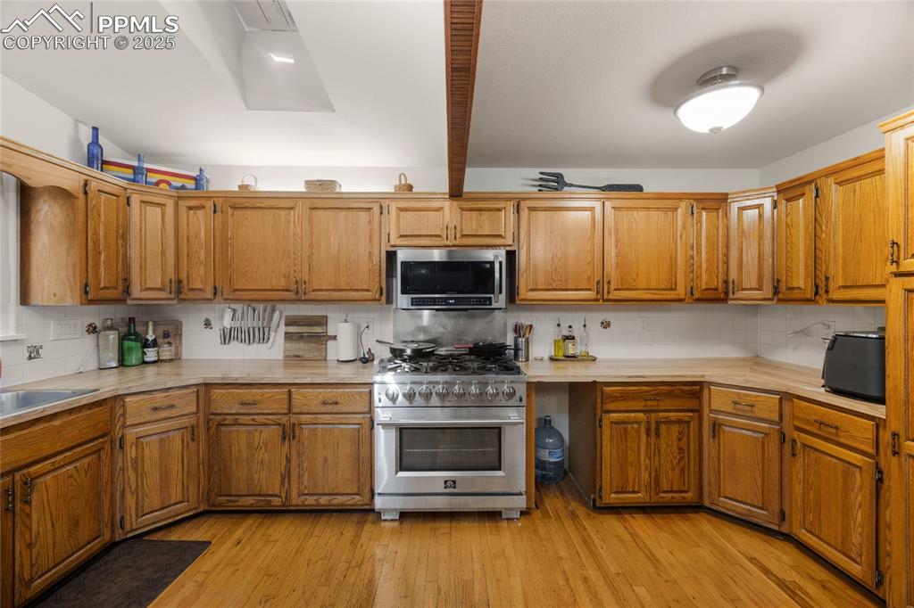 Image 7 of 15: Kitchen featuring tasteful backsplash, light countertops, appliances with s