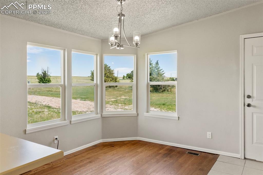 Image 12 of 34: Unfurnished dining area with healthy amount of natural light, a textured ce