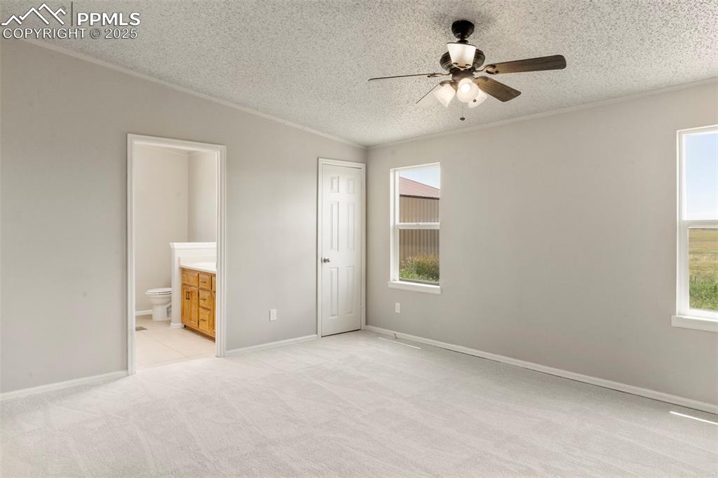 Image 13 of 34: Unfurnished bedroom featuring a textured ceiling, light carpet, connected b