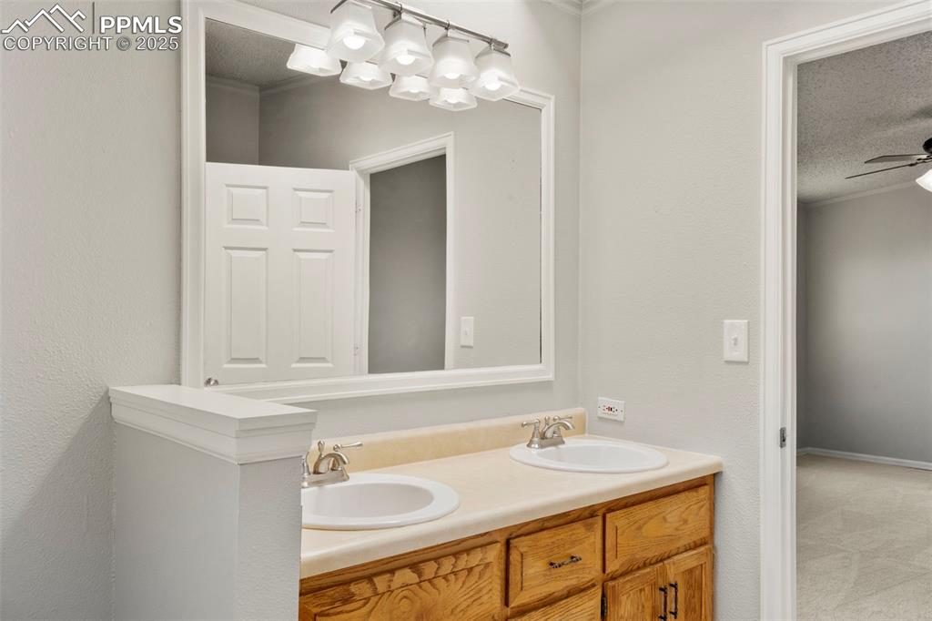 Image 15 of 34: Bathroom with a textured ceiling, ornamental molding, double vanity, and a
