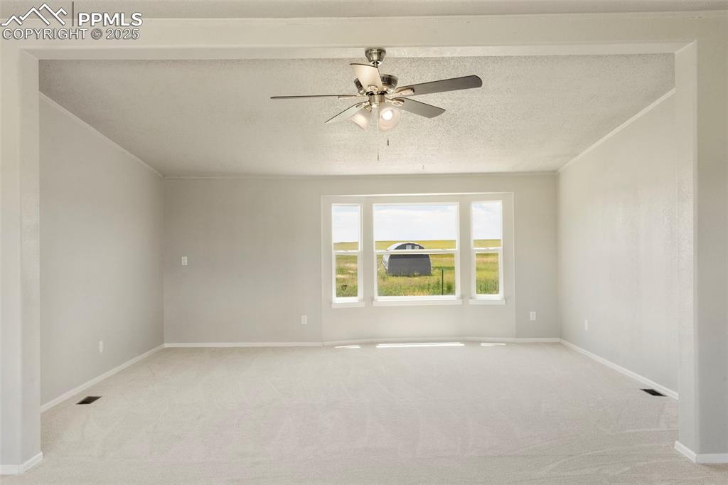 Image 5 of 34: Empty room with light colored carpet and ceiling fan