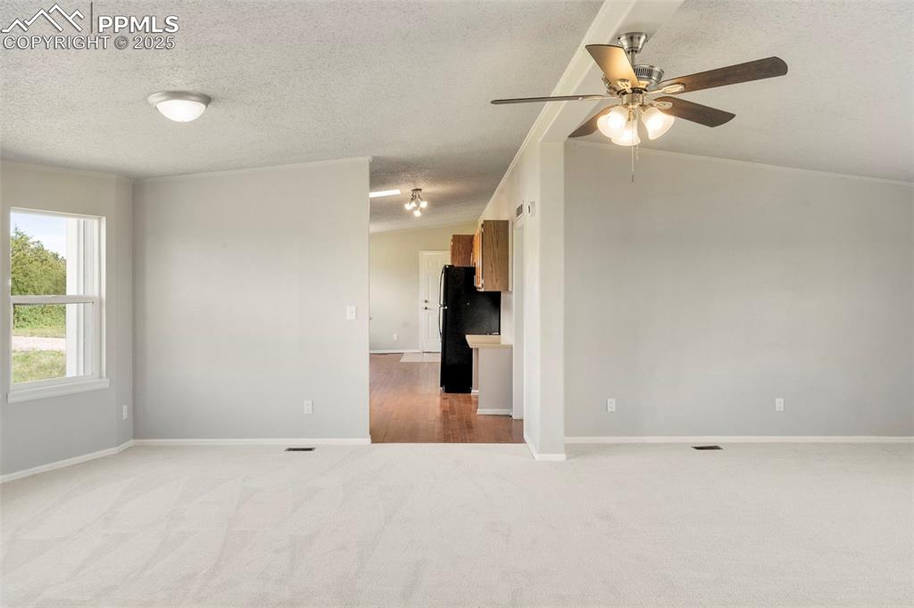 Image 6 of 34: Unfurnished room with carpet floors, a ceiling fan, and a textured ceiling