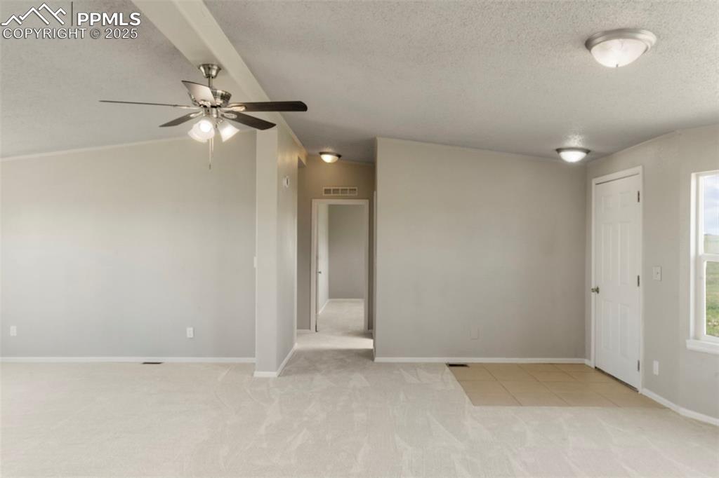 Image 7 of 34: Spare room with light colored carpet, a textured ceiling, ceiling fan, and