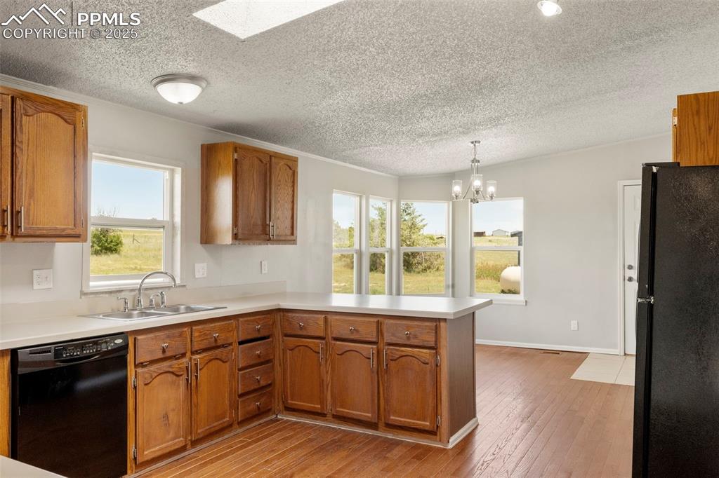 Image 9 of 34: Kitchen with black appliances, a peninsula, a textured ceiling, brown cabin