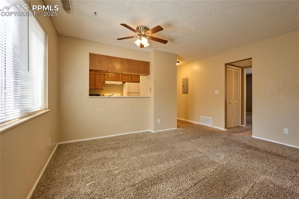 Image 10 of 24: Living/Dining room with carpet floors and a ceiling fan