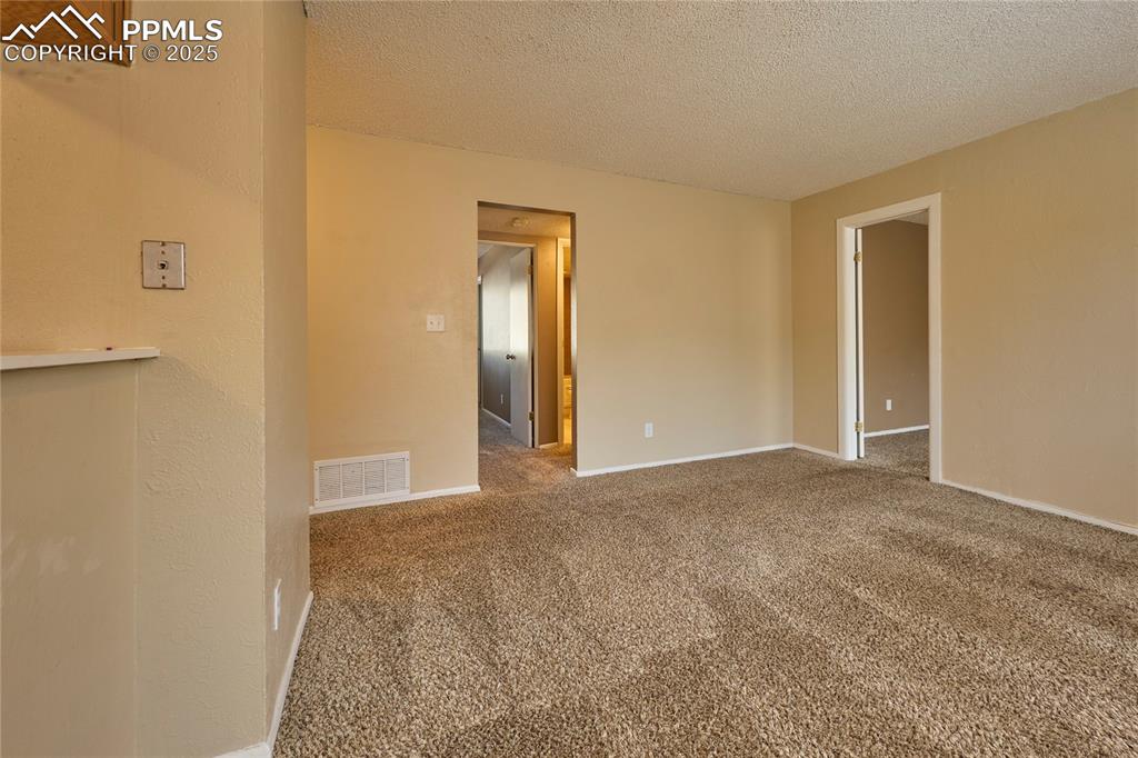 Image 11 of 24: Carpeted spare room with baseboards, visible vents, and a textured ceiling