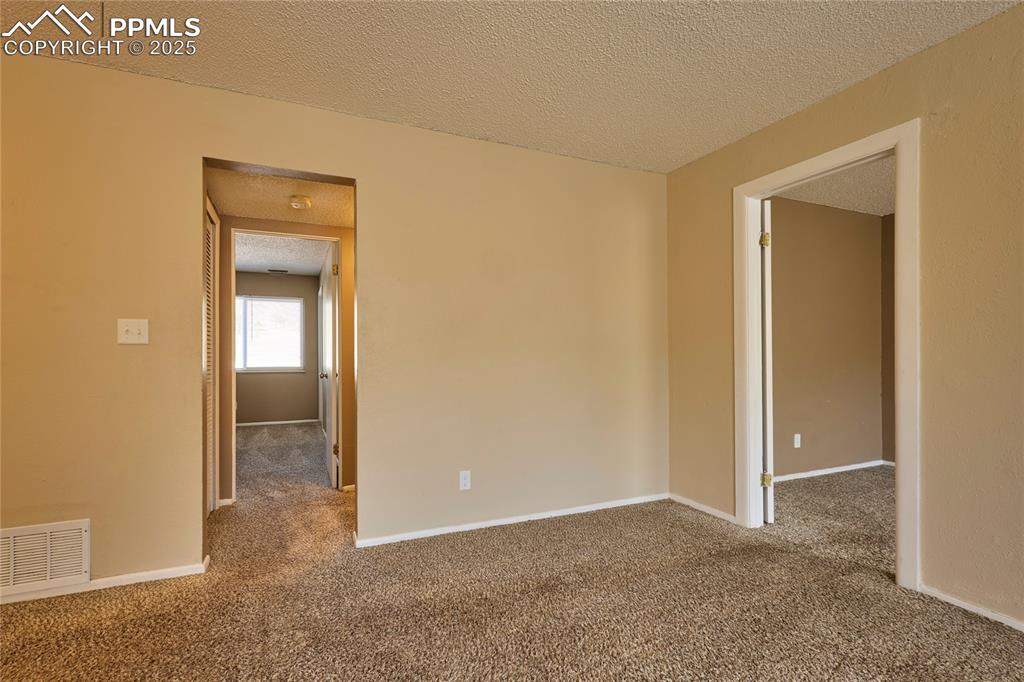Image 13 of 24: Spare room with a textured ceiling, carpet, visible vents, and baseboards