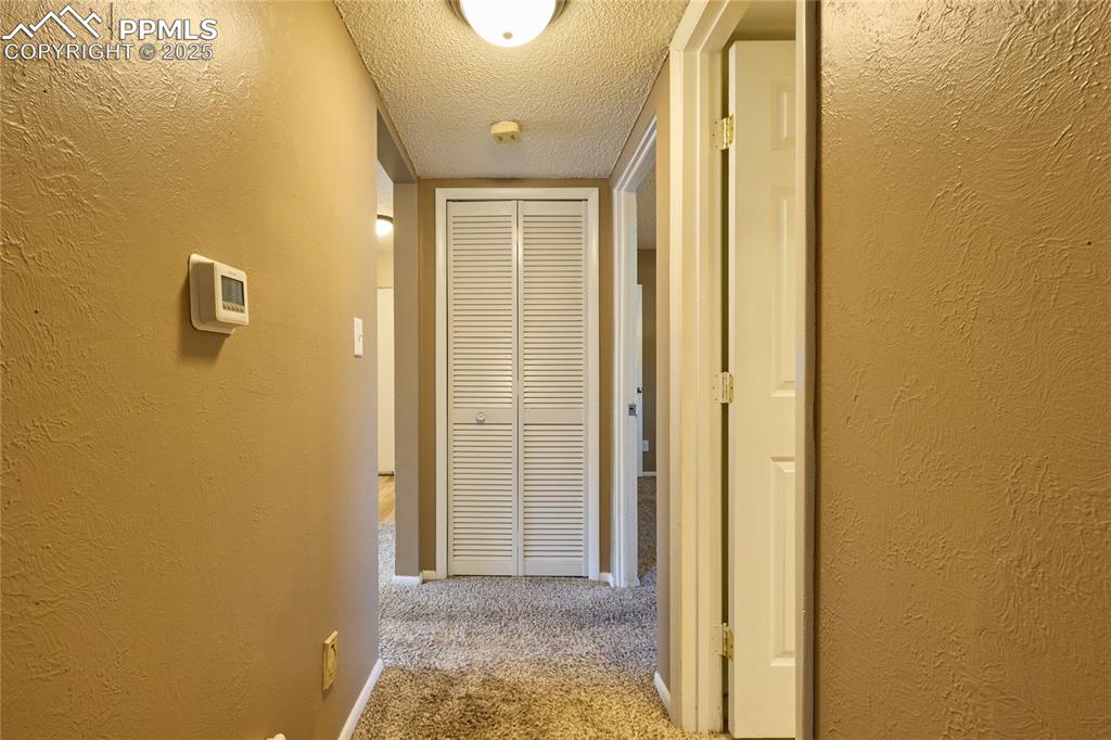 Image 16 of 24: Hallway with carpet floors, a textured wall