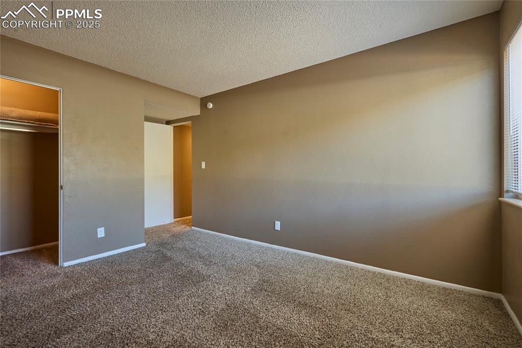 Image 18 of 24: Unfurnished bedroom with a spacious closet, carpet floors, a closet, basebo
