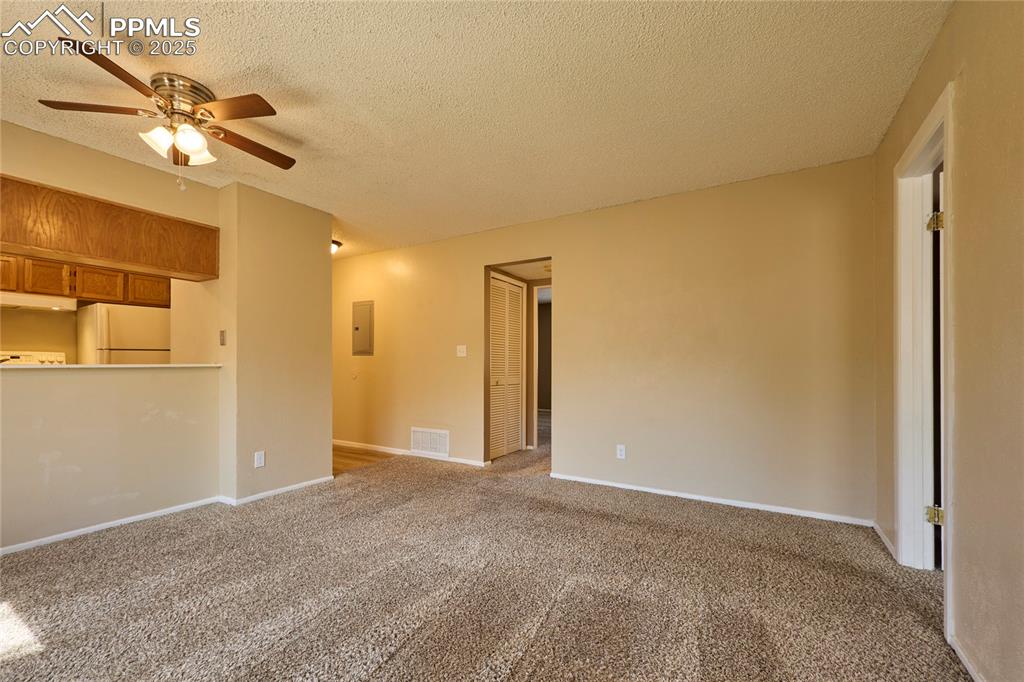Image 9 of 24: Unfurnished living room with visible vents, electric panel, a textured ceil