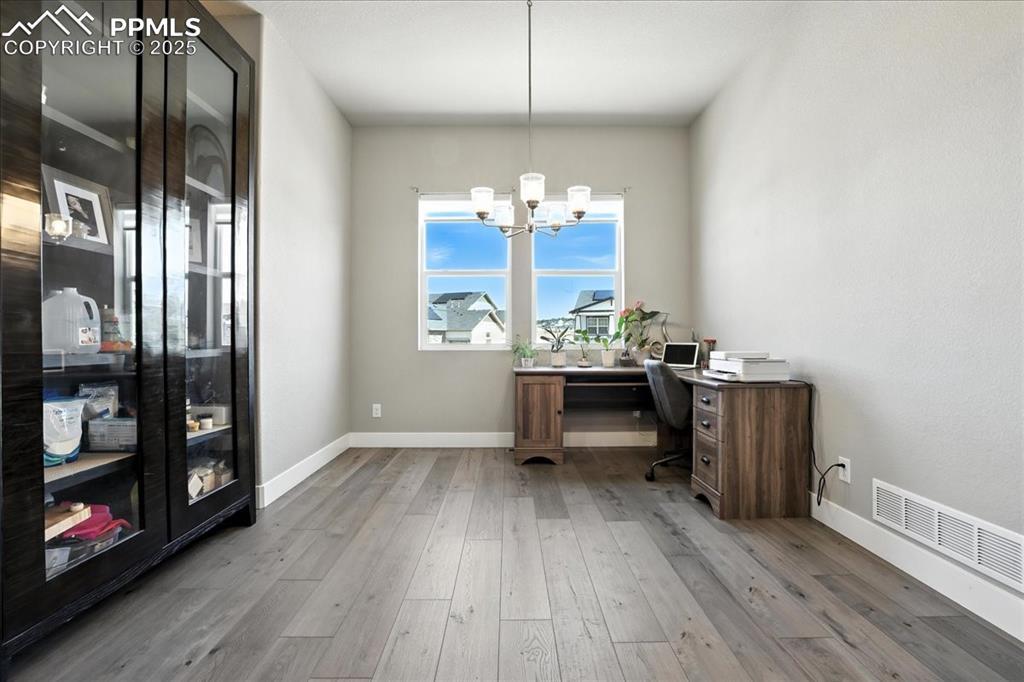 Image 12 of 50: Office area featuring wood finished floors and a chandelier