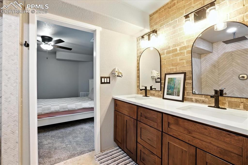 Image 31 of 50: Ensuite bathroom with double vanity, a ceiling fan, and a shower