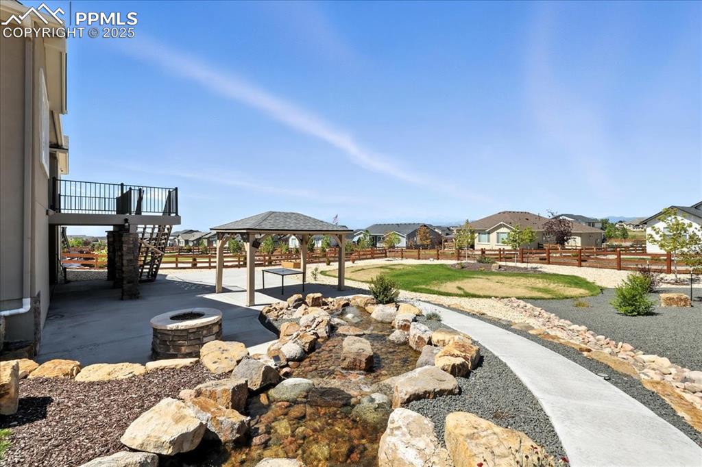Image 38 of 50: Fenced backyard featuring a residential view, a gazebo, a fire pit, a patio