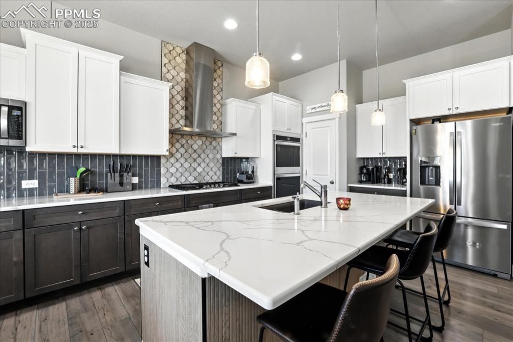 Image 4 of 50: Kitchen featuring stainless steel appliances, decorative backsplash, white