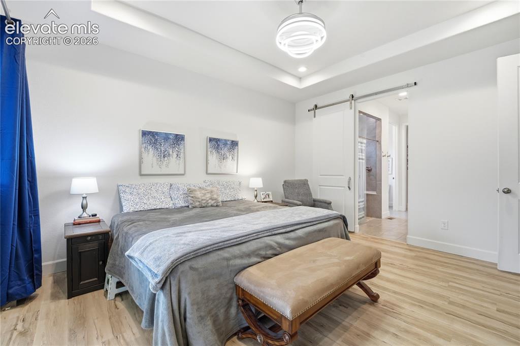 Image 23 of 50: Spacious Primary bedroom featuring barn door and modern remote ceiling fixt