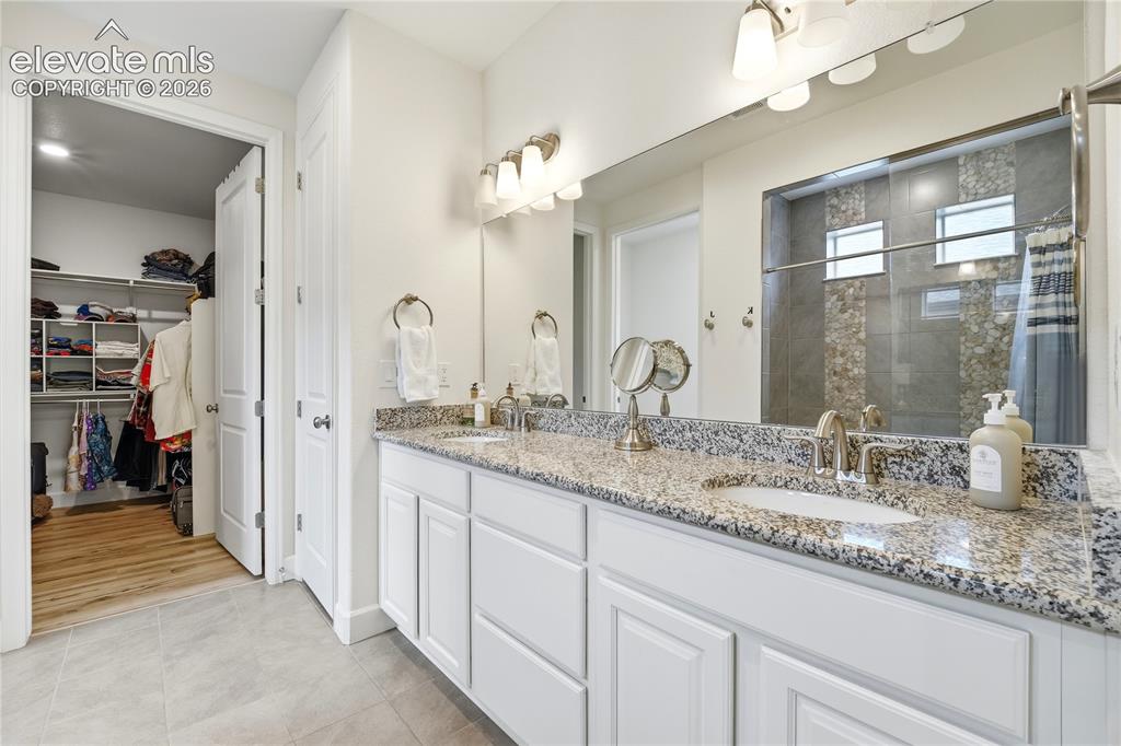 Image 24 of 50: Bathroom featuring a double vanity with granite countertop, white cabinetry