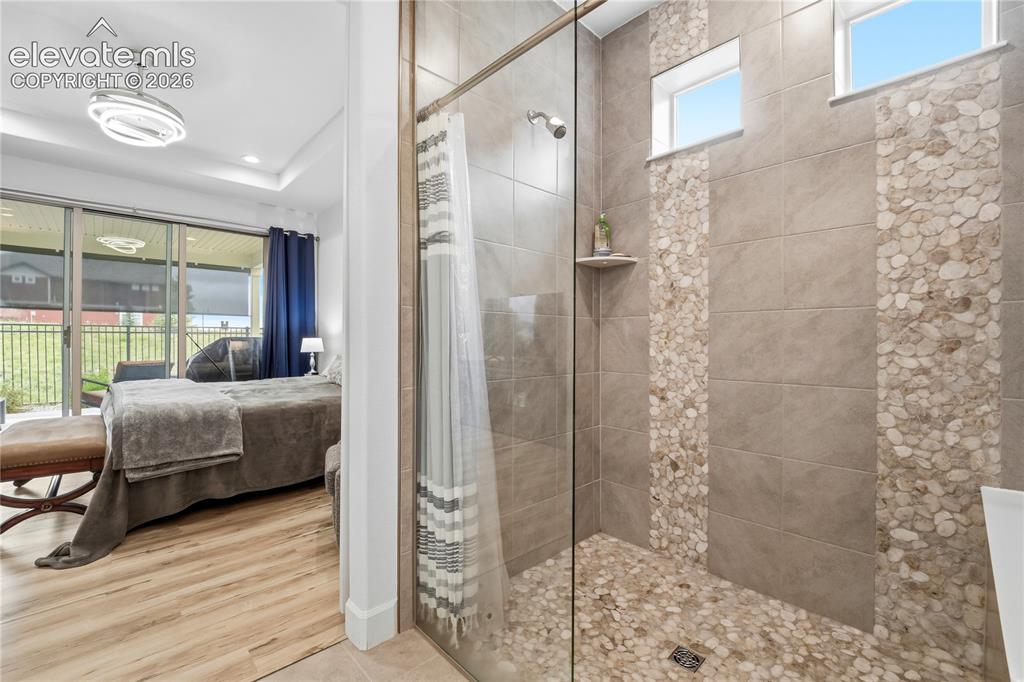 Image 25 of 50: Shower with glass enclosure, pebble-tile flooring, and pebble-tile accent s