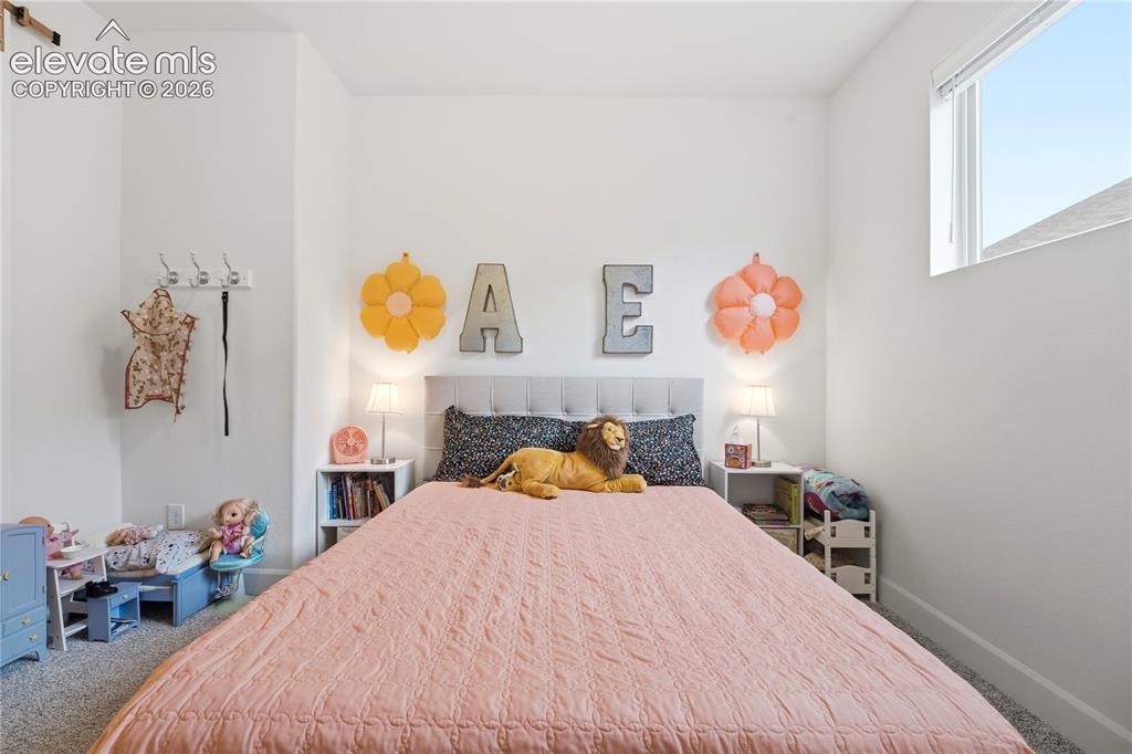 Image 28 of 50: Bedroom featuring high ceilings, white walls, and a large window