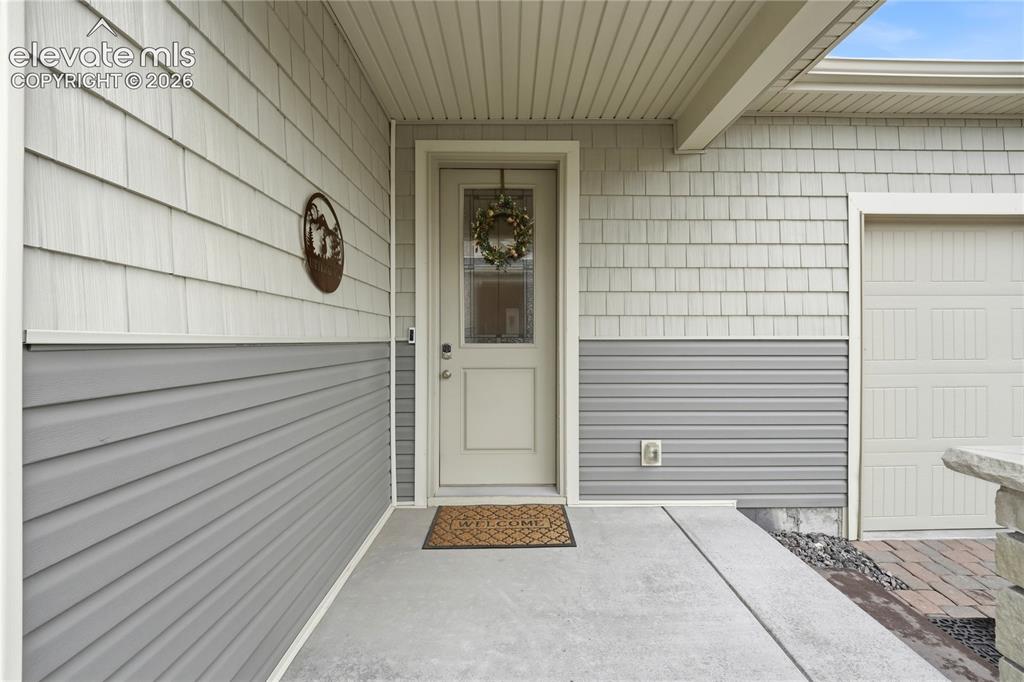 Image 3 of 50: Covered front door entryway with decorative glass insert. 