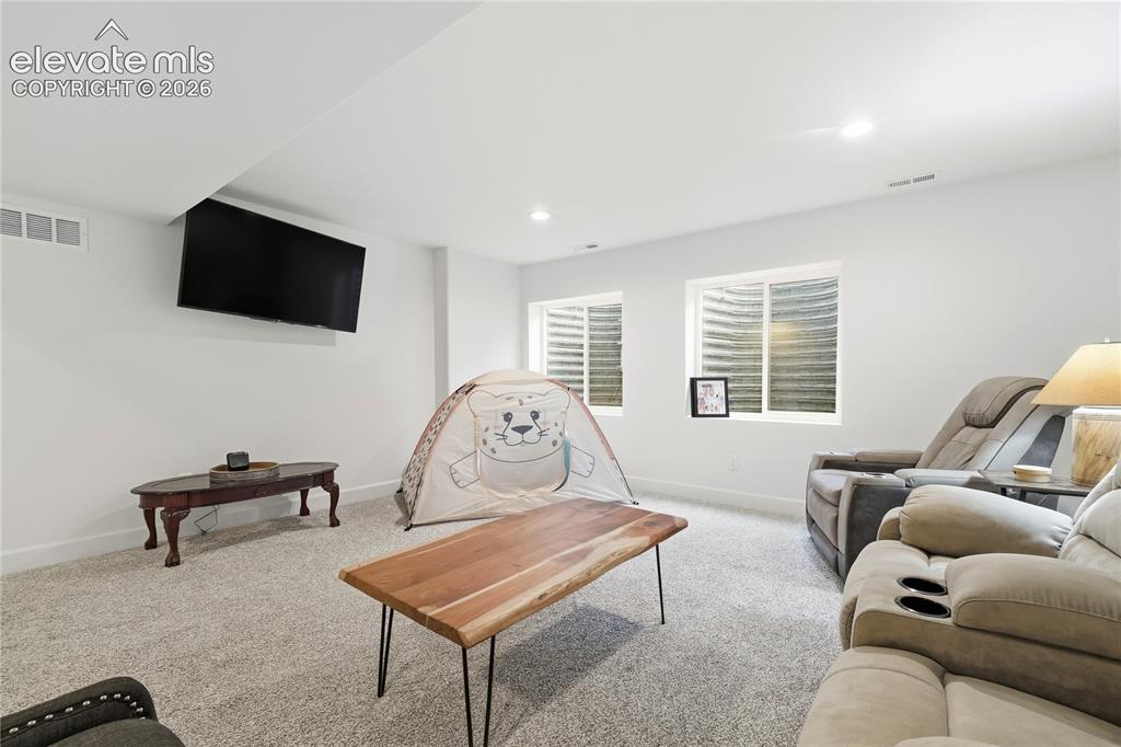 Image 32 of 50: Family room with a wall-mounted television and recessed lighting