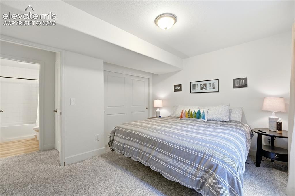 Image 37 of 50: Carpeted bedroom featuring a flush-mount ceiling light, white walls, and bi