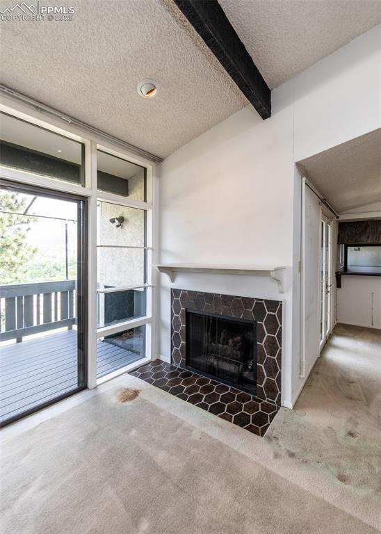 Image 10 of 40: Unfurnished living room featuring a textured ceiling, carpet floors, a fire