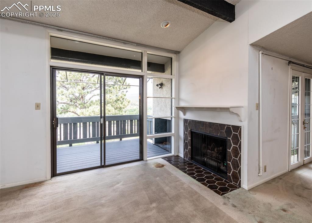 Image 11 of 40: Unfurnished living room featuring carpet, a textured ceiling, and a stone f