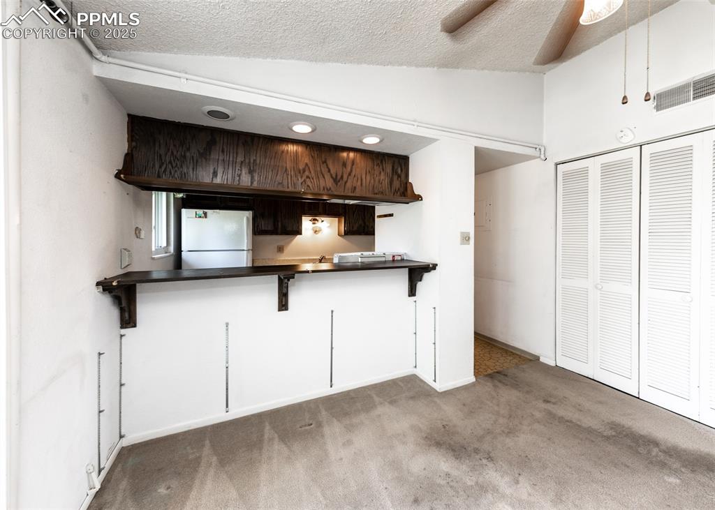 Image 17 of 40: Kitchen featuring carpet floors, freestanding refrigerator, dark countertop