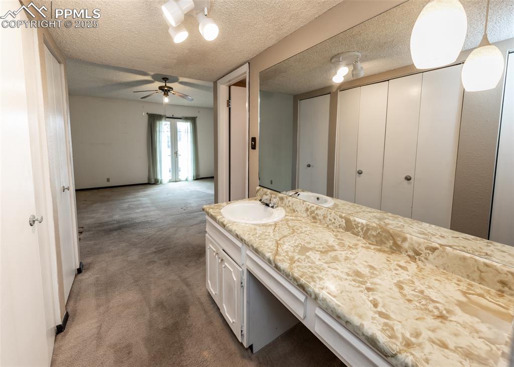 Image 24 of 40: Bathroom featuring Mastervanity, a textured ceiling, ceiling fan, and frenc