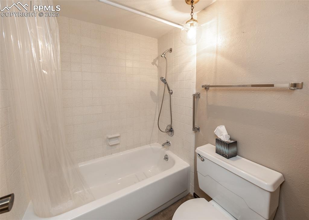 Image 26 of 40: Full bathroom with shower / bathtub combination with curtain and a textured