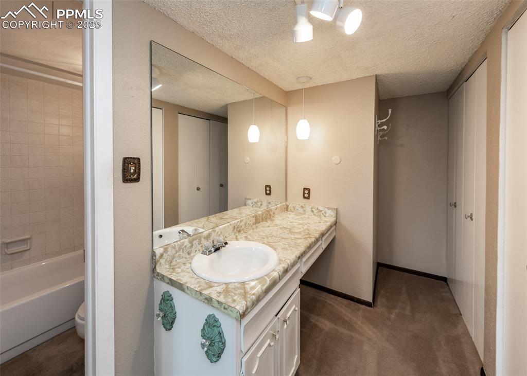 Image 28 of 40: Full bath featuring vanity, a textured ceiling, and bathing tub / shower co