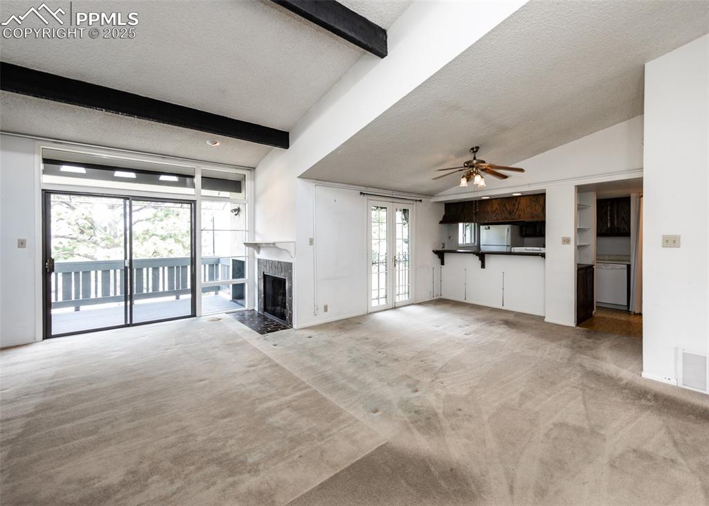 Image 7 of 40: Unfurnished living room with a fireplace, light carpet, a textured ceiling,
