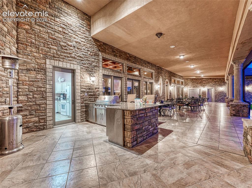 Image 11 of 50: Outdoor kitchen with gas grill is connected to a smaller, indoor kitchen ar