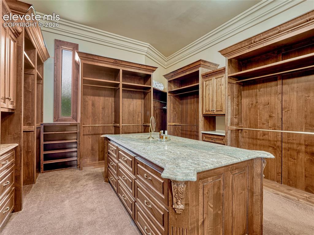 Image 31 of 50: Primary suite walk-in closet with island for additional storage space.