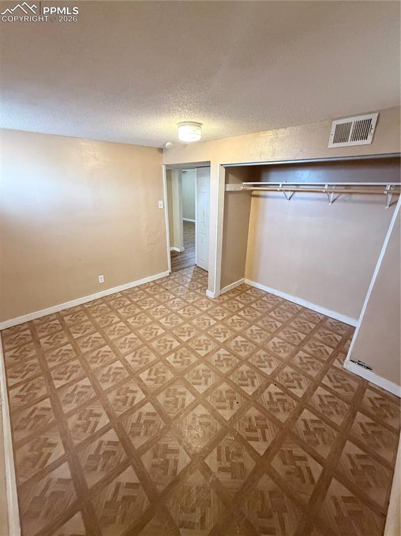 Image 10 of 15: Unfurnished bedroom featuring a closet and a textured ceiling