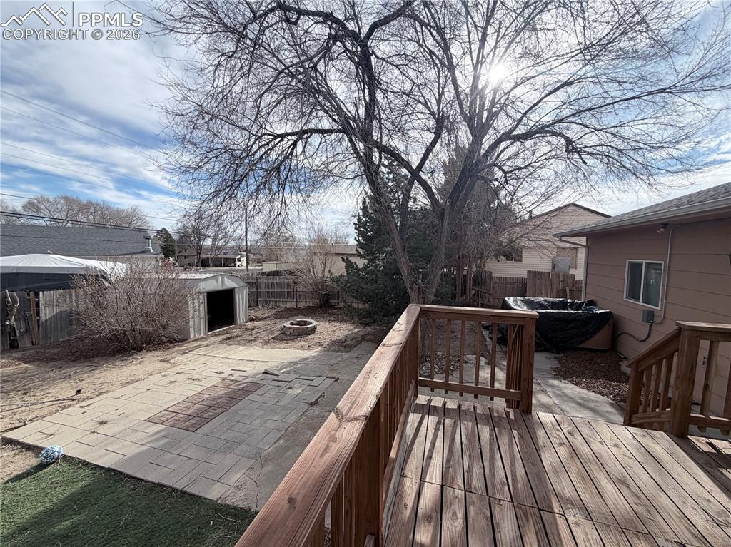 Image 14 of 15: Deck featuring a fire pit, a fenced backyard, and a patio