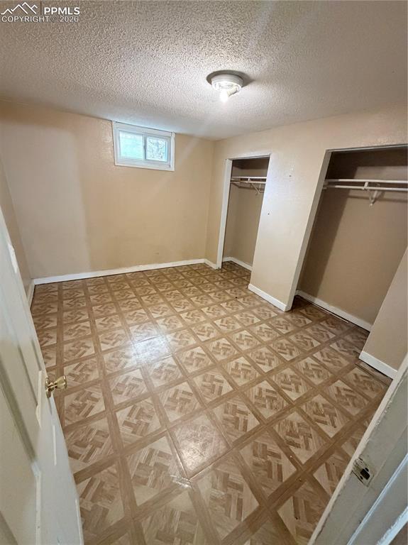 Image 9 of 15: Unfurnished bedroom featuring two closets, a textured ceiling, and light fl