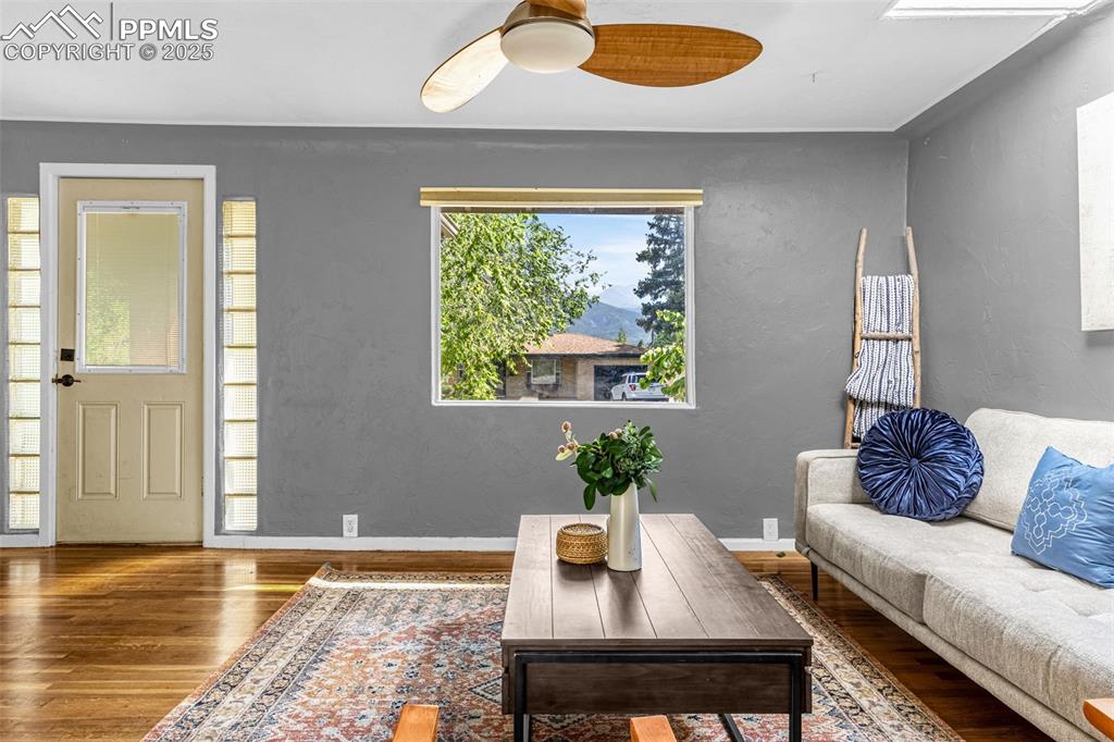 Image 11 of 42: Living room featuring wood finished floors, ceiling fan, and a mountain vie