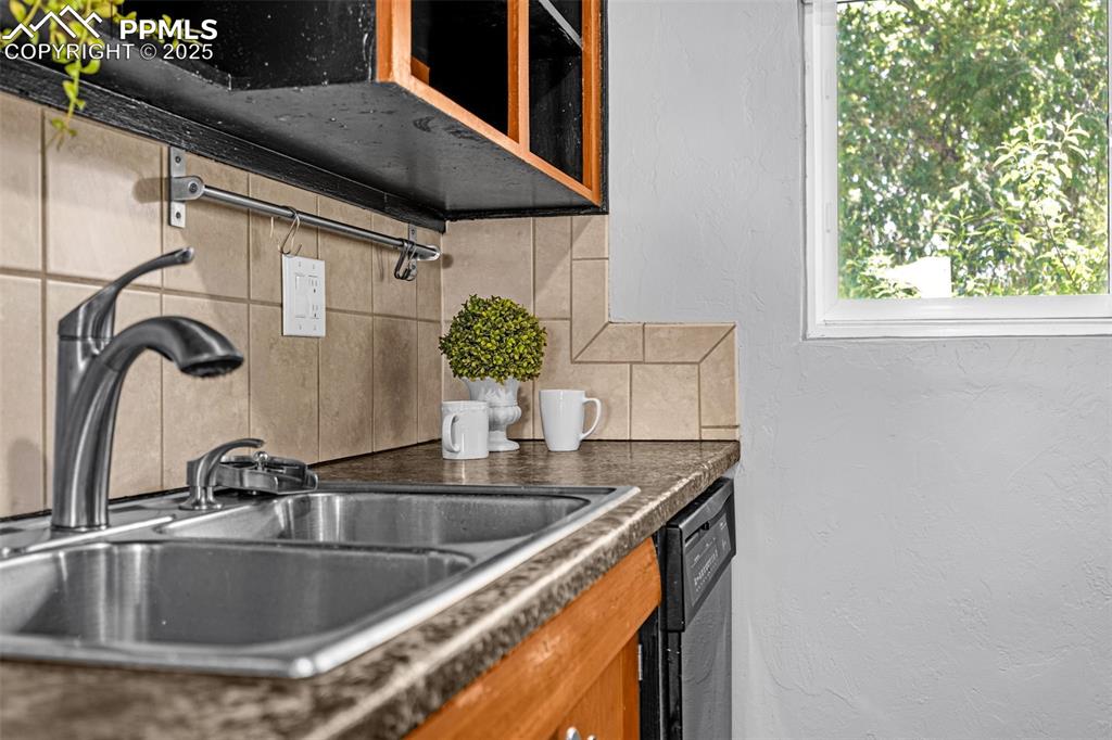 Image 17 of 42: Kitchen with decorative backsplash, dishwasher, dark countertops, and a tex