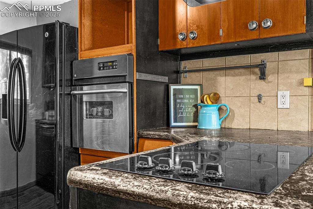 Image 18 of 42: Kitchen featuring black appliances, tasteful backsplash, brown cabinetry, a