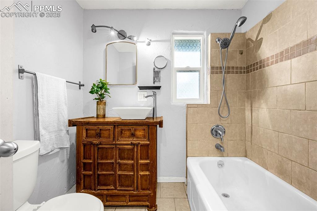 Image 19 of 42: Bathroom with tile patterned floors, vanity, and washtub / shower combinati