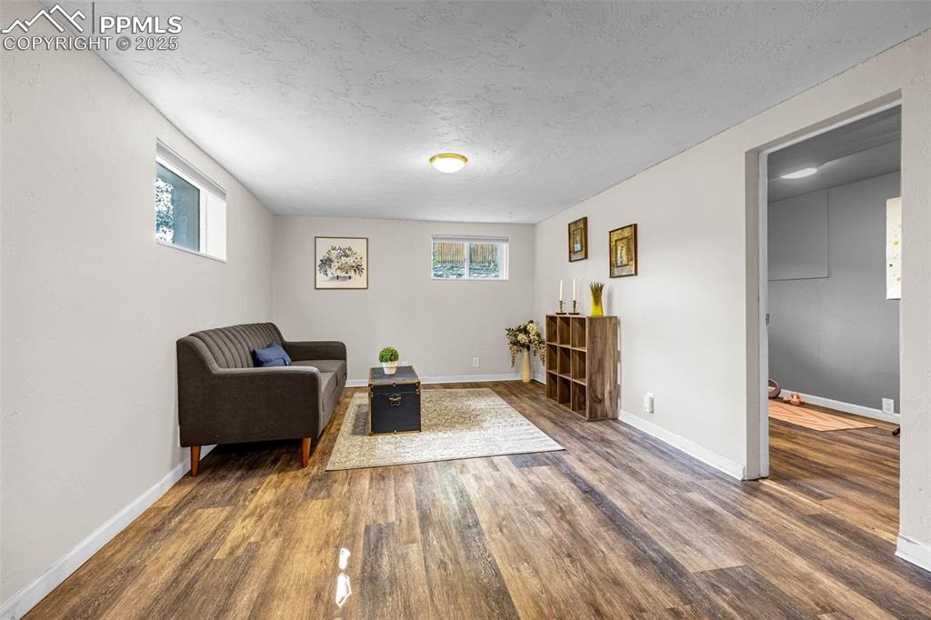 Image 24 of 42: Sitting room with wood finished floors, plenty of natural light, and a text