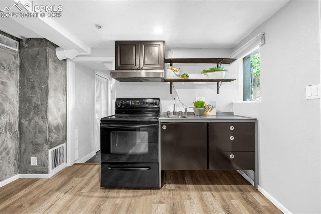 Image 27 of 42: Kitchen with black range with electric cooktop, under cabinet range hood, l