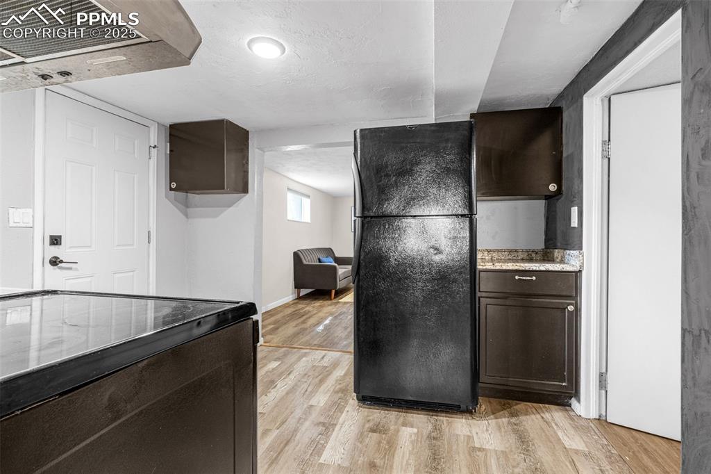 Image 28 of 42: Kitchen with black appliances, light wood-type flooring, dark brown cabinet