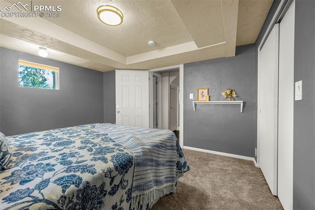 Image 31 of 42: Carpeted bedroom featuring a raised ceiling, a textured ceiling, and a text